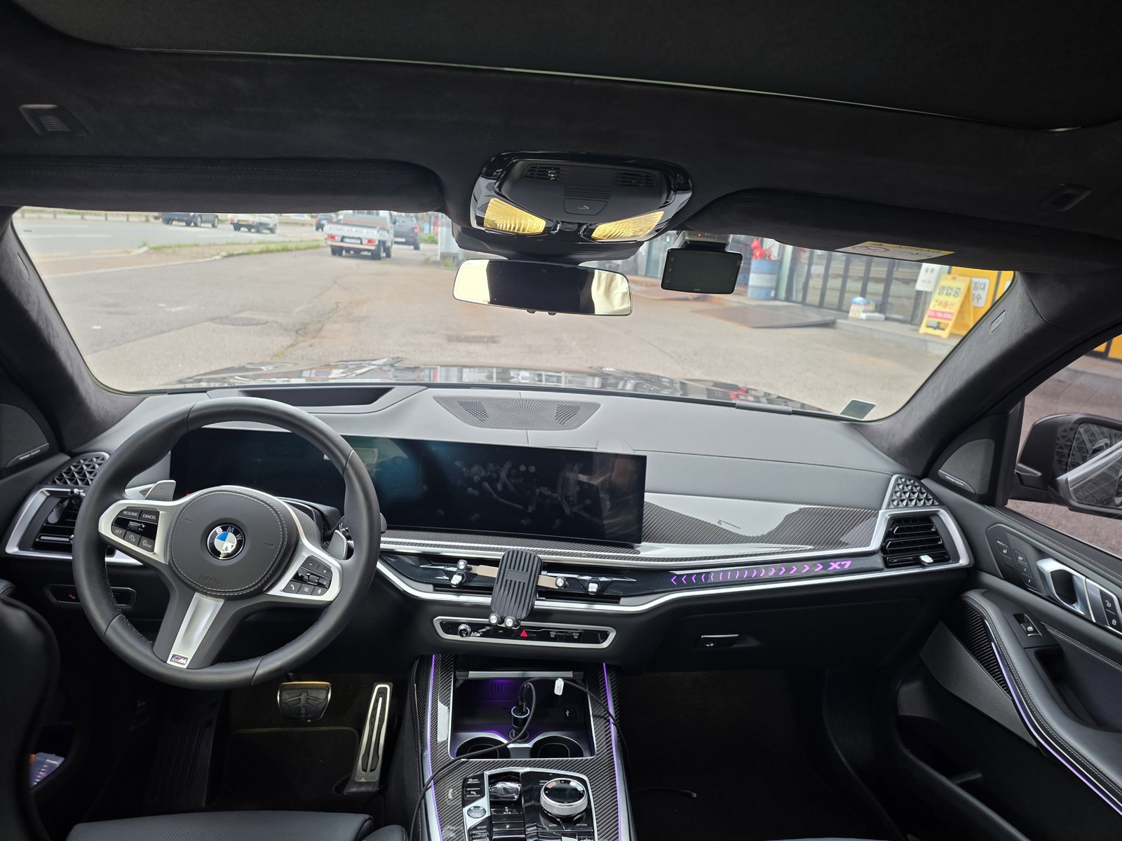 BMW X7 대시보드. 커브드 디스플레이 아래에 물리 버튼과 다이얼이 남아 있다.