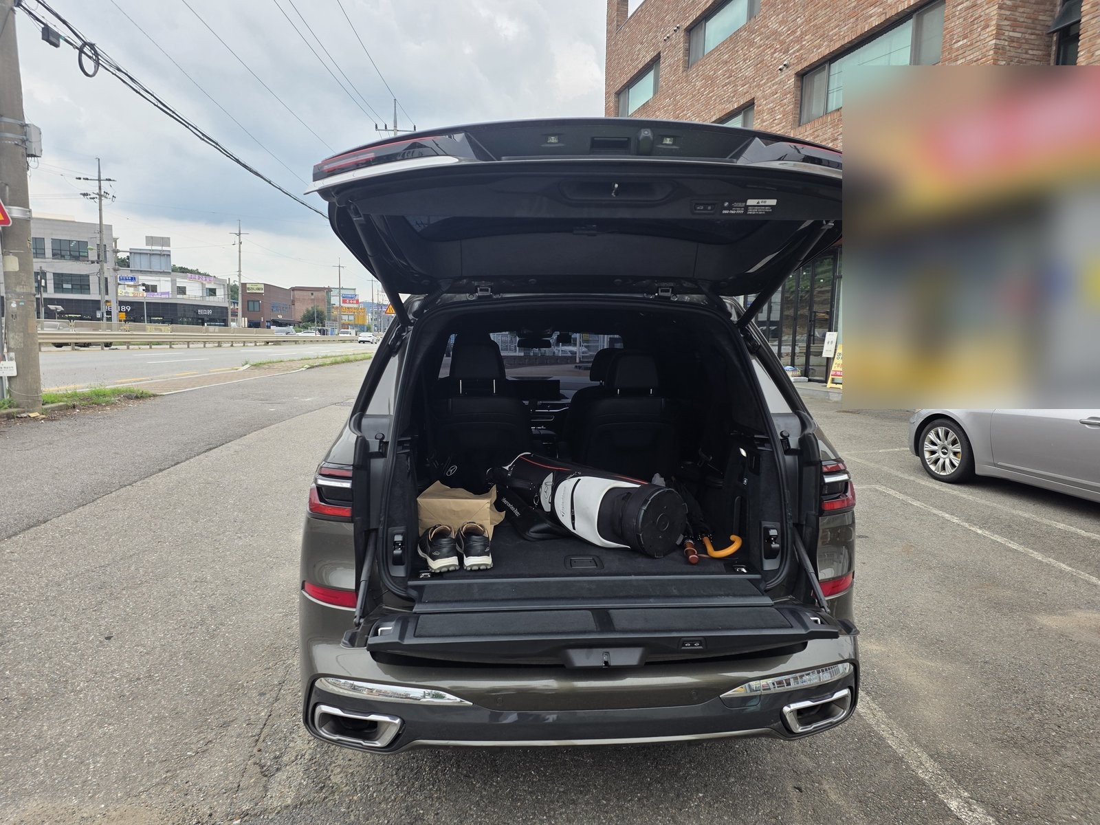 BMW X7 트렁크. 클램쉘 테일게이트 아래쪽 게이트를 내린 상태로 3열을 접고 골프백을 실었다.