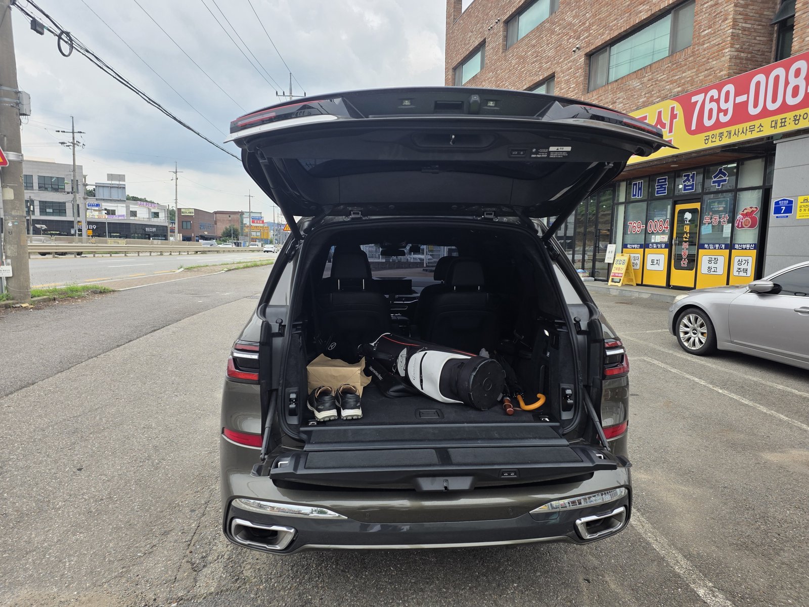 BMW X7 트렁크. 클램쉘 테일게이트 아래쪽 게이트를 내린 상태로 3열을 접고 골프백을 실었다.